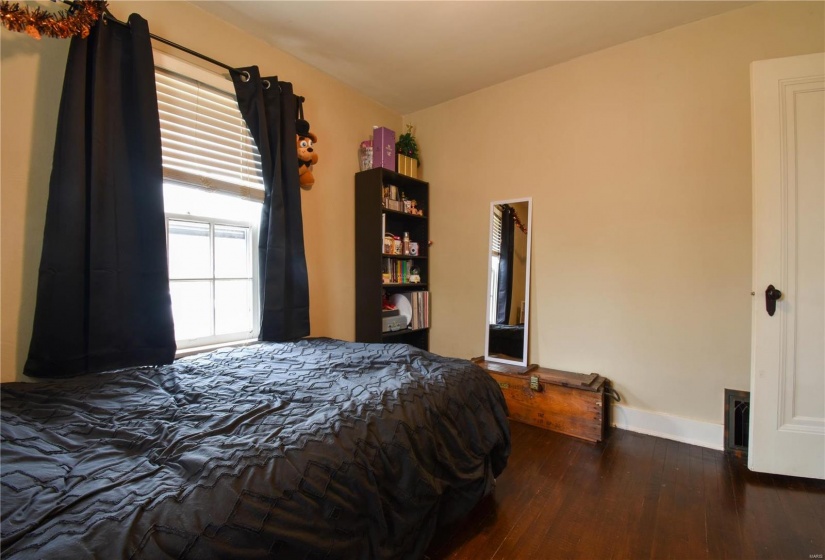 Bedroom with dark hardwood / wood-style flooring