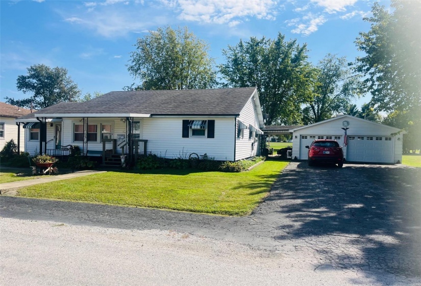 View of front facade with covered porch, a front lawn, an outbuilding, and a garage